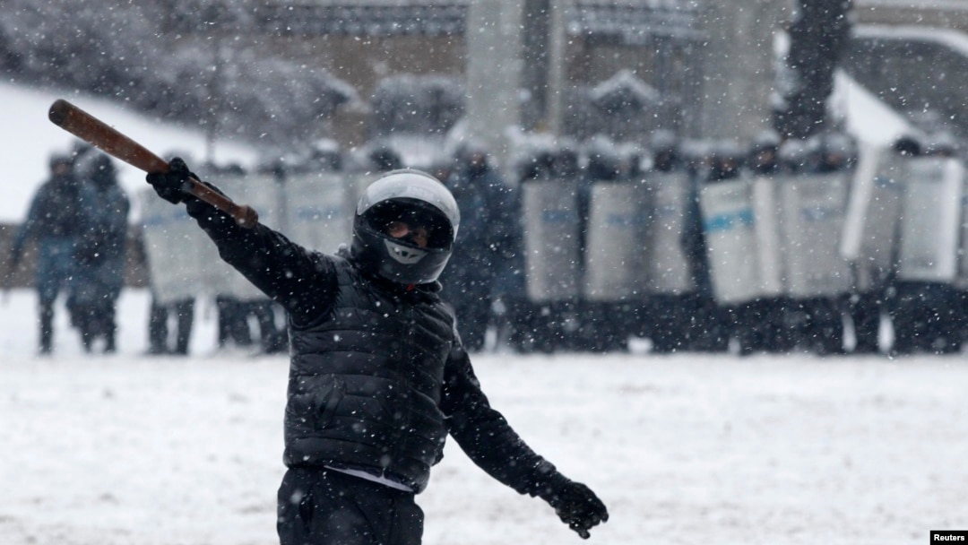 A pro-European protester gestures, with riot police officers seen in the background, during a rally in Kyiv, Jan. 22, 2014.