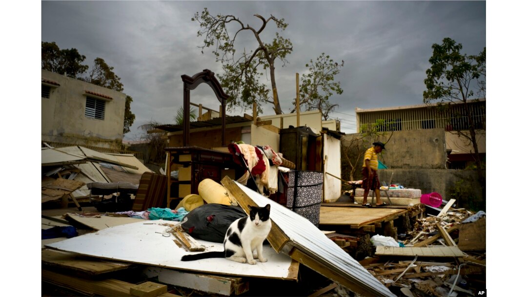 Efrain Diaz Figueroa, right, walks by his sister's home destroyed in the passing of Hurricane Maria, in San Juan, Puerto Rico, Oct. 9, 2017.