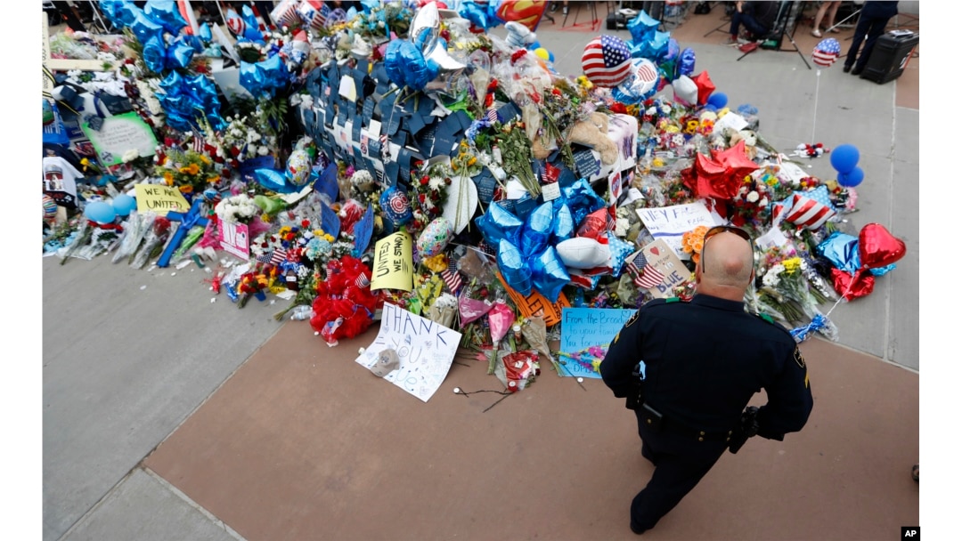 A policeman visits a makeshift memorial at the Dallas police headquarters, July 11, 2016, in Dallas.