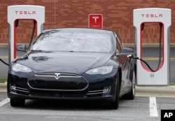 FILE - A Tesla car recharges at a charging station in Charlotte, N.C., June 24, 2017.