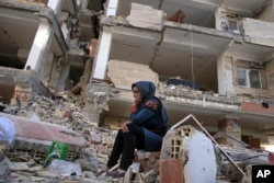 An earthquake survivor sits on debris in front of his house in a compound, which was built under the Mehr state-owned program, in Sarpol-e-Zahab in western Iran, Nov. 14, 2017.