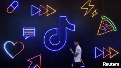 在浙江杭州，一名男子持手機走過抖音/TikTok的標識。(2019年10月18日)