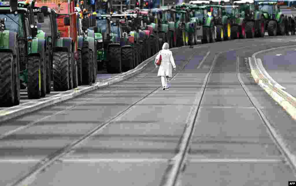 A woman walks past tractors as farmers protest against the government's agricultural policy including plans to phase out glyphosate pesticides and to implement more animal protection, during a demonstration in Bonn, western Germany.