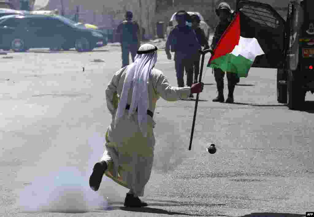 A Palestinian demonstrator runs past a tear gas canister launched by Israeli forces during a protest in solidarity with Palestinian prisoners held in Israeli jails near Israel's Ofer Prison in the occupied West Bank.
