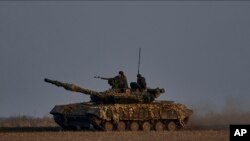 Soldados ucranianos viajan sobre un tanque en la línea del frente en Bájmut, región de Donetsk, Ucrania, el miércoles 22 de marzo de 2023. (AP Photo/Libkos)