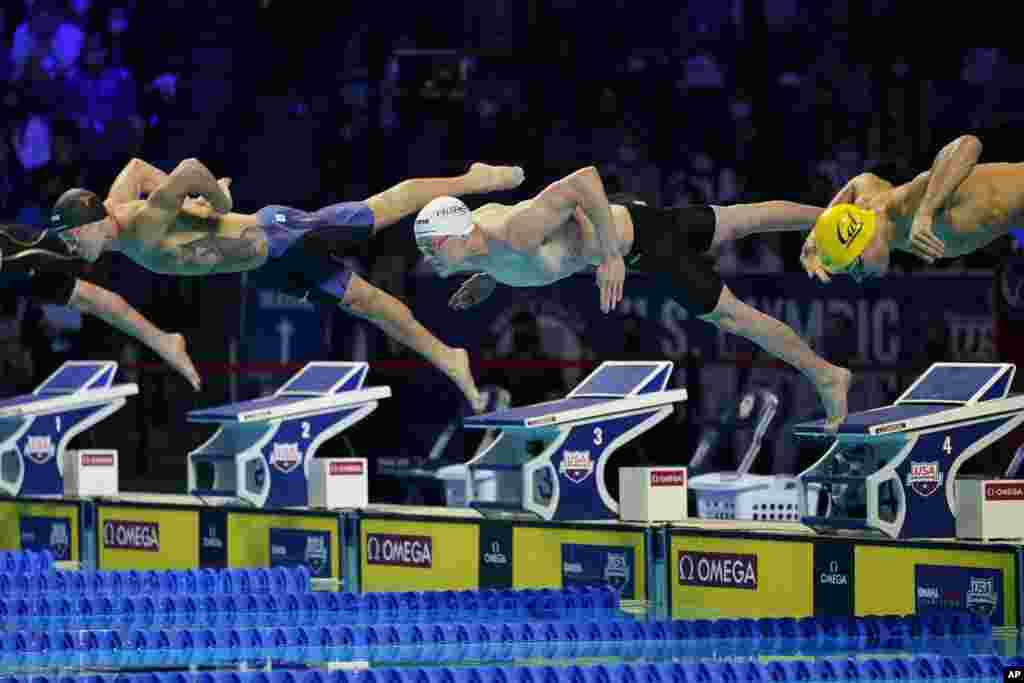 Drew Kibler, left, Patrick Callan, center, and Andrew Seliskar, right, dive at the start of a men's 100-meter freestyle semifinal during wave 2 of the U.S. Olympic Swim Trials, June 14, 2021, in Omaha, Nebraska.
