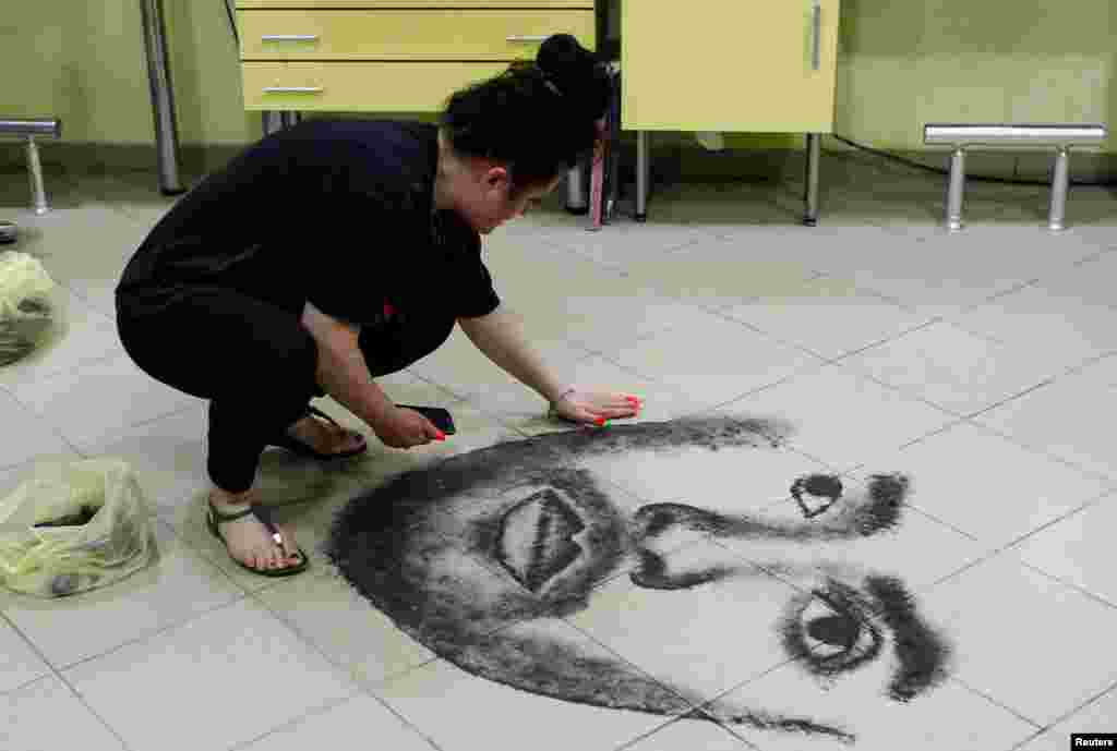 Hairdresser Svetlana Grozdanovska creates a celebrity's portrait on the floor of her salon using her clients' cut hair, in Krivogastani, North Macedonia.