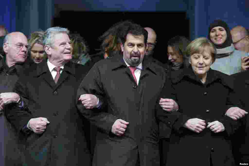 Bundestag President Norbert Lammert, German President Joachim Gauck, Chairman of the Central Council of Muslims in Germany Aiman Mazyek and German Chancellor Angela Merkel, link arms during a vigil organized by Muslim groups for the victims of the terror shooting by gunmen at the offices of Charlie Hebdo, in front of the Brandenburg Gate in Berlin, January 13, 2015.