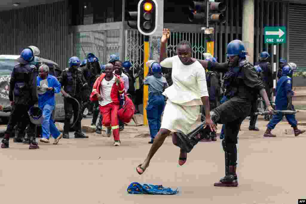 An anti-riot policeman tackles a woman as they dispersed a crowd gathered to hear an address by Nelson Chamisa, leader of the MDC (Movement for Democratic Change) Alliance, at Morgan Tsvangirai House, the party headquarters in Harare, Zimbabwe.