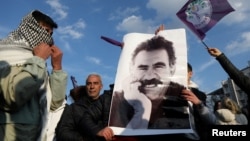 Dos jóvenes muestran un cartel con la imagen de Abdullah Ocalan, el encarcelado líder del Partido de los Trabajadores del Kurdistán, o PKK, en Diyarbakir, Turquía, el 27 de febrero de 2025.