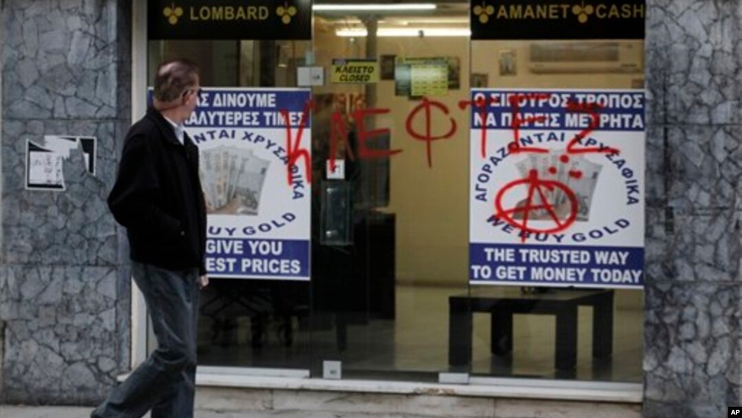 Man passes entrance of a store that buys gold vandalized with Greek word "thievess," Nicosia, Cyprus, March 25, 2013.