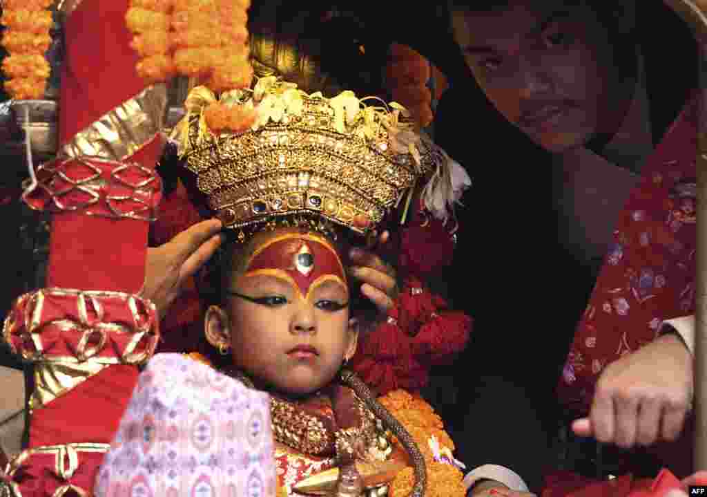 A Nepali child revered as a living goddess, or Kumari, is carried in a chariot during a procession on the main day of the Indra Jatra festival at Basantapur Durbar Square in Kathmandu.