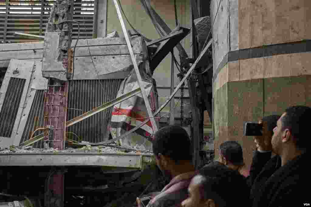 Passengers take photos of the locomotive wreck. (H. Elrasam/VOA)