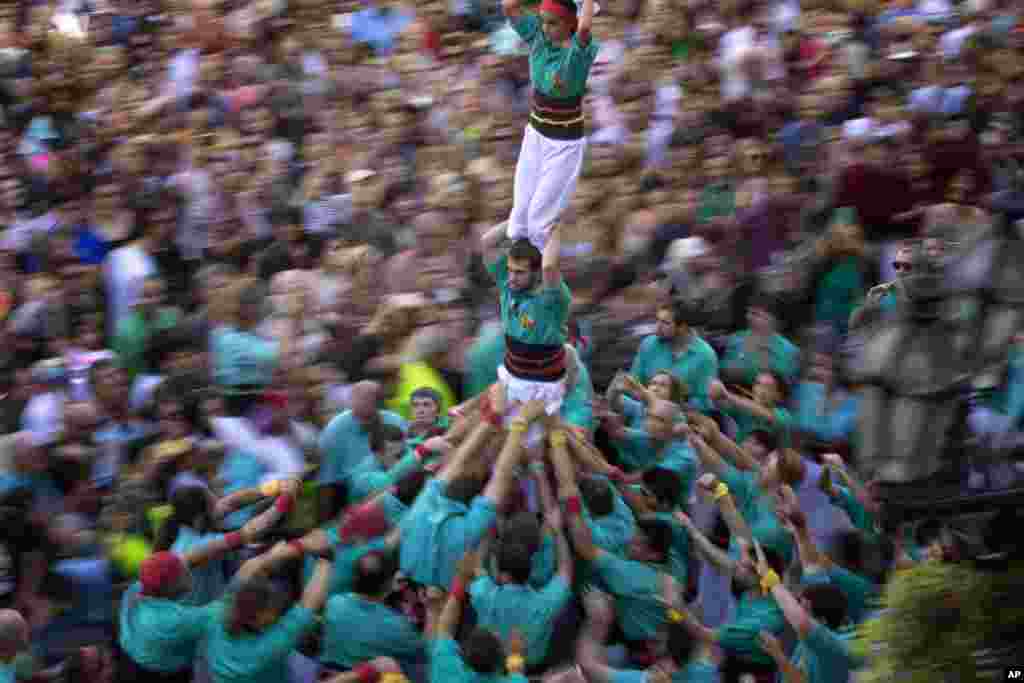 Participants walk maintaining a human tower or "Castellers" during the Saint Merce celebrations in San Jaume square in Barcelona, Spain.