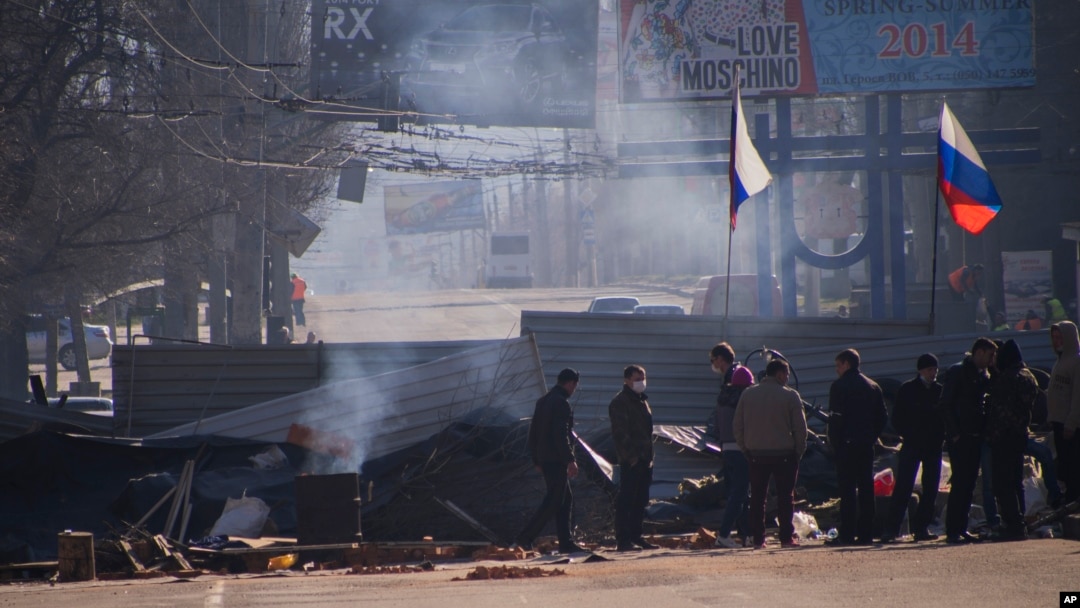 Pro-Russia activists are seen behind a barricade with Russian flags in front an entrance of a regional office of Ukraine's Security Service in Luhansk, April 8, 2014.