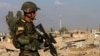A Kurdish Peshmerga fighter walks past a house destroyed by American air strikes at Barznki village two days ago in Zummar, controlled by Islamic State (IS), near Mosul, Sept. 15, 2014. 