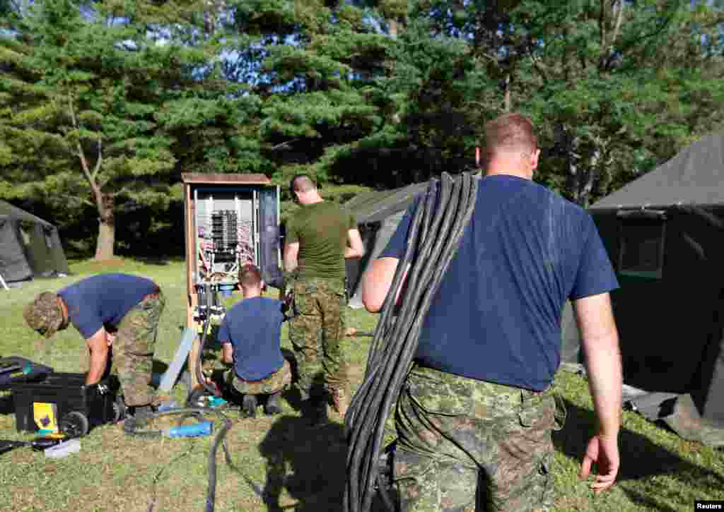 Members of the Canadian Armed Forces install electricity for the tents erected to house asylum seekers at the Canada-U.S. border in Lacolle, Quebec, Aug. 9, 2017.