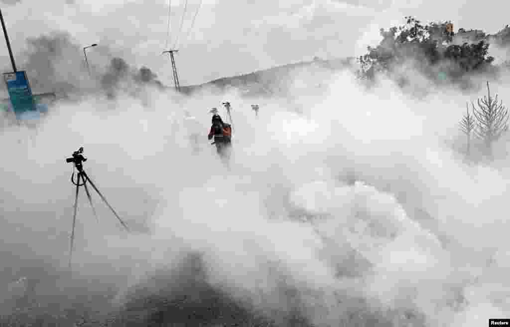 A journalist reacts to tear gas fired by Israeli forces during a Palestinian protest near the Jewish settlement of Beit El, in the Israeli-occupied West Bank, Sept. 9, 2019.