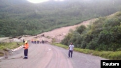 Locals inspect a landslide and damage to a road located near the township of Tabubil after an earthquake that struck Papua New Guinea's Southern Highlands, February 26, 2018. This image was supplied by a 3rd party.