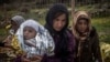 FILE - Women and children stand on a road after their arrival on a dinghy with other refugees and migrants from the Turkish coast to the Greek island of Lesbos, Nov. 25, 2015.