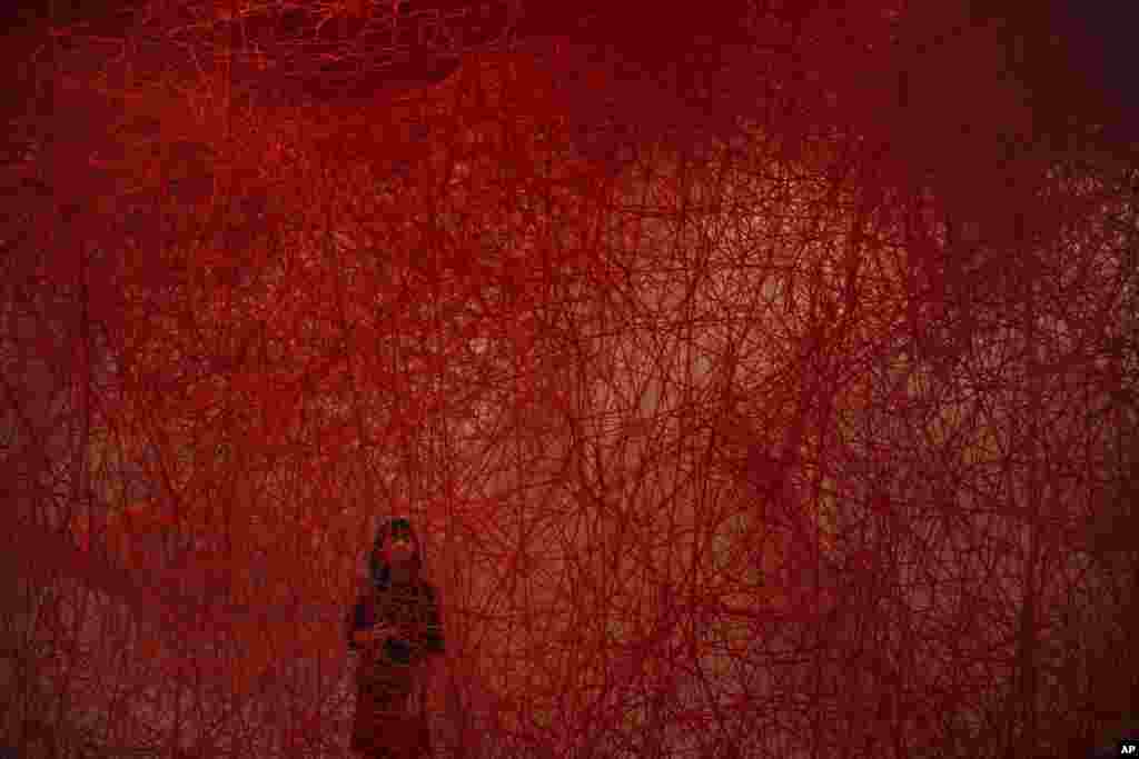 A woman looks at Chiharu Shiota's art installation titled "Uncertain Journey" at the Mori Art Museum in Tokyo, Japan.