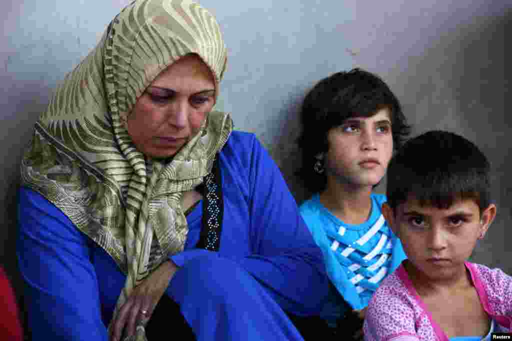 A Syrian refugee sits with her daughters where they are staying temporarily with their relatives in Wadi Khaled town, Lebanon, July 24, 2012.
