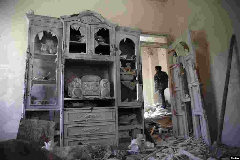 A boy inspects a damaged house in the rebel held besieged city of Douma, a suburb of Damascus, Syria, Feb. 27, 2016.