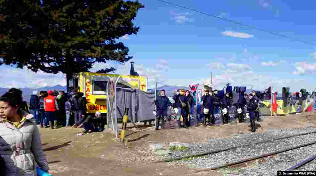 Police officers cluster at a fence in the northern Greek border town of Idomeni, where migrants await permission to pass into Macedonia.