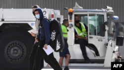 Tennis players and officials disembark from a flight after arriving in Melbourne on January 14, 2021, to quarantine ahead of the Australian Open tennis tournament. (Photo by William WEST / AFP)