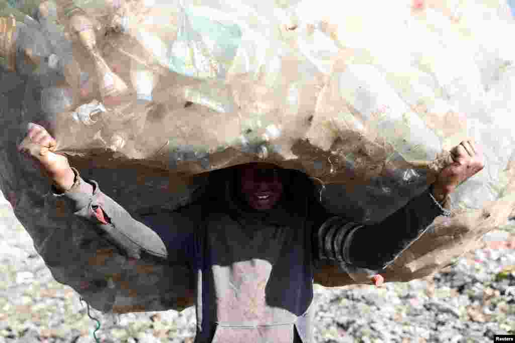 A man carries a sack full of plastic bottles in the Andralanitra garbage dump in Antananarivo, Madagascar.