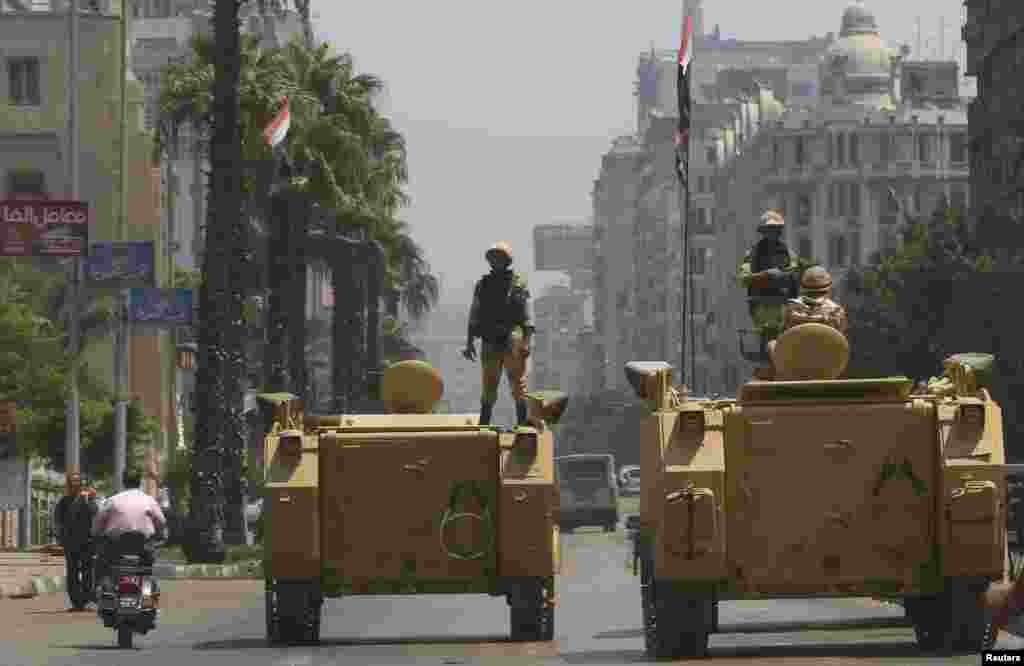 A soldier holds his weapon as he stands on an armored personnel carrier positioned outside the state-run television station in Cairo, August 16, 2013.