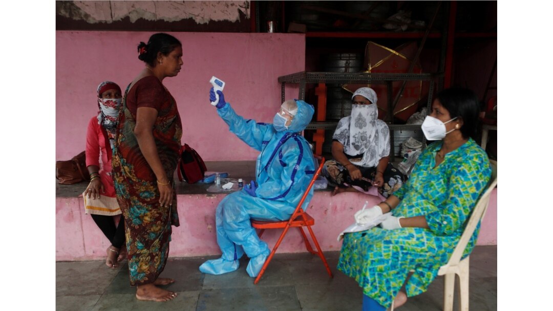 A health worker in personal protective equipment (PPE) checks the temperature of a resident with an electronic thermometer during a check up campaign for the coronavirus disease (COVID-19), in Mumbai, India, July 13, 2020.