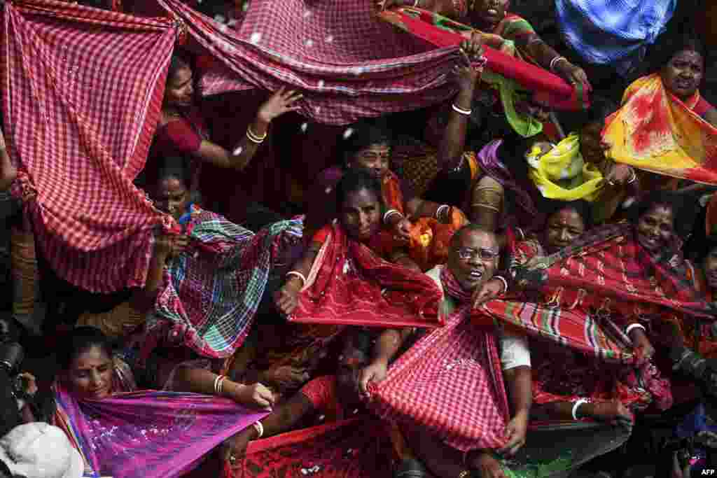 Hindu devotees collect rice as offerings distributed by the temple authority on the occasion of the 'Annakut' or 'Govardhan Puja' festival at the Madan Mohan temple in Kolkata, India.
