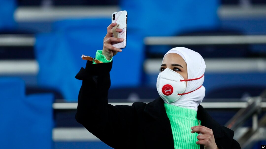 Una aficionada con cubrebocas toma una fotografía con su teléfono celular antes del duelo de los octavos de final de la Liga de Campeones entre el Real Madrid y el Manchester City en el Estadio Santiago Bernabéu de Madrid, el miércoles 26 de febrero de 2020.