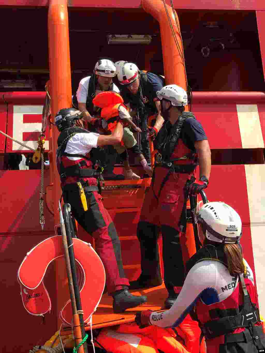 Crew members of the 'Ocean Viking' rescue ship, operated by French NGOs SOS Mediterranee and Medecins sans Frontieres (MSF), help a child climb on board from an inflatable rescue dinghy, during their first rescue operation in the Mediterranean Sea.