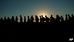ARCHIVO - Migrantes que cruzaron el Río Grande y entraron a EEUU desde México hacen fila para ser procesados por la Oficina de Aduanas y Protección Fronteriza de EEUU, el 23 de septiembre de 2023, en Eagle Pass, Texas.