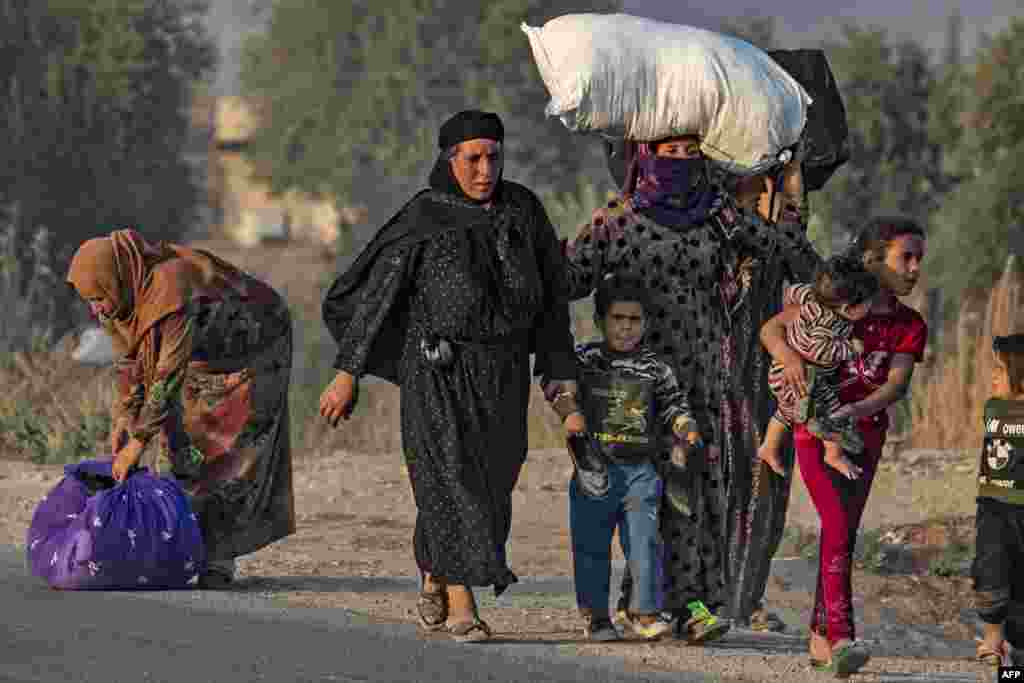 Civilians flee during Turkish bombardment on Syria's northeastern town of Ras al-Ain in the Hasakeh province along the Turkish border.
