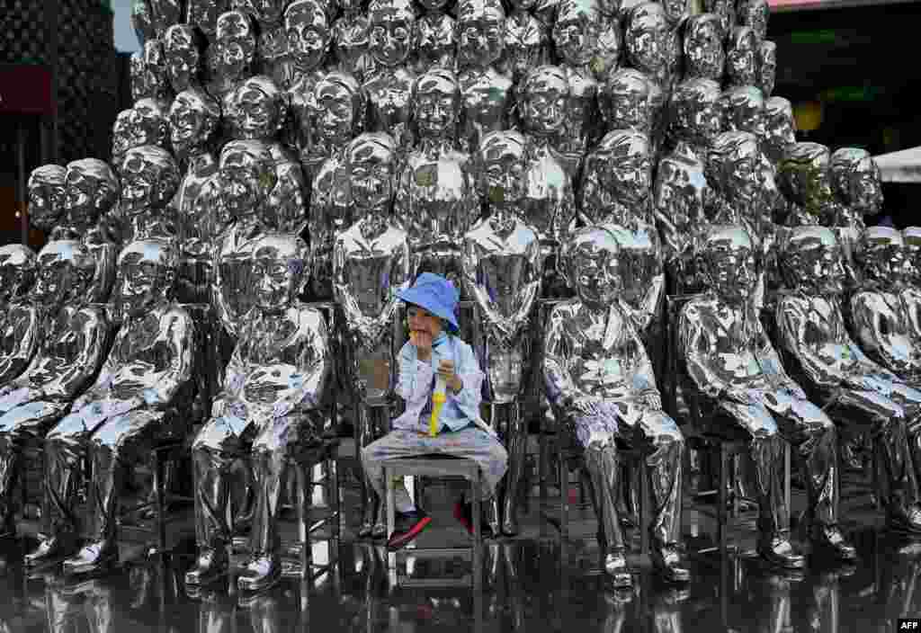A boy sits on a chair amongst sculptures on display at a shopping center on International Children's Day in Beijing. China announced it would allow couples to have three children.