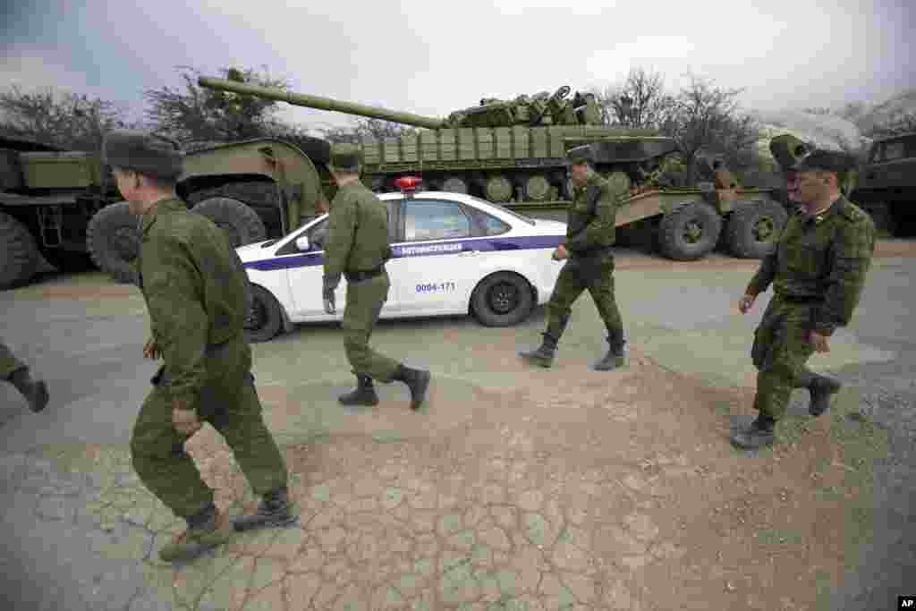 Xe cảnh sát và binh lính Nga đi phía sau xe tăng của Ukraine tại Perevalnoe, bên ngoài Simferopol, Crimea, ngày 26/3/2014.