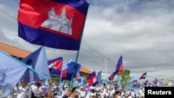 Supporters from the Candlelight Party wave flags at a campaign rally in Phnom Penh on May 21, 2022. (Prak Chan Thul/Reuters) 