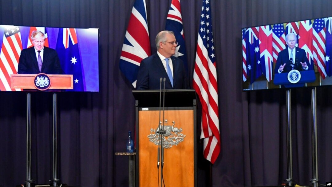 Australia's Prime Minister Scott Morrison, center, appears on stage with video links to Britain's Prime Minister Boris Johnson, left, and U.S. President Joe Biden at a joint press conference at Parliament House in Canberra, Sept. 16, 2021.