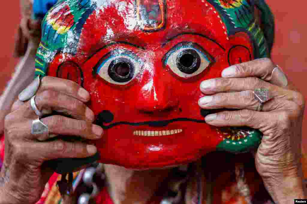 A person adjusts a clay mask while preparing to take part in a deity's procession during the Shikali festival at Khokana, in Lalitpur, Nepal.