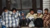 FILE - Children sit under covers as they wait with migrants and refugees near the registration camp in the town of Presevo after their arrival in Serbia, on Sept. 10, 2015. 
