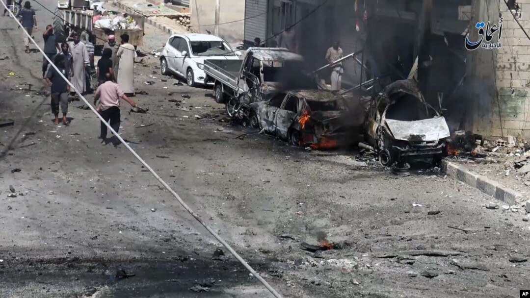 FILE - Syrian citizens gather near burned cars after airstrikes hit Manbij, in Aleppo province, Syria, in this undated image posted online on July 28, 2016, by supporters of the Islamic State militant group on an anonymous photo sharing website.