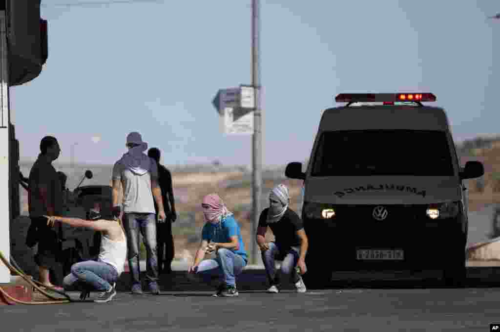 Palestinians take cover during clashes with Israeli soldiers following a protest against the Israeli military action in Gaza, at an area near the Beit El Jewish settlement and the West Bank city of Ramallah, July 25, 2014. 