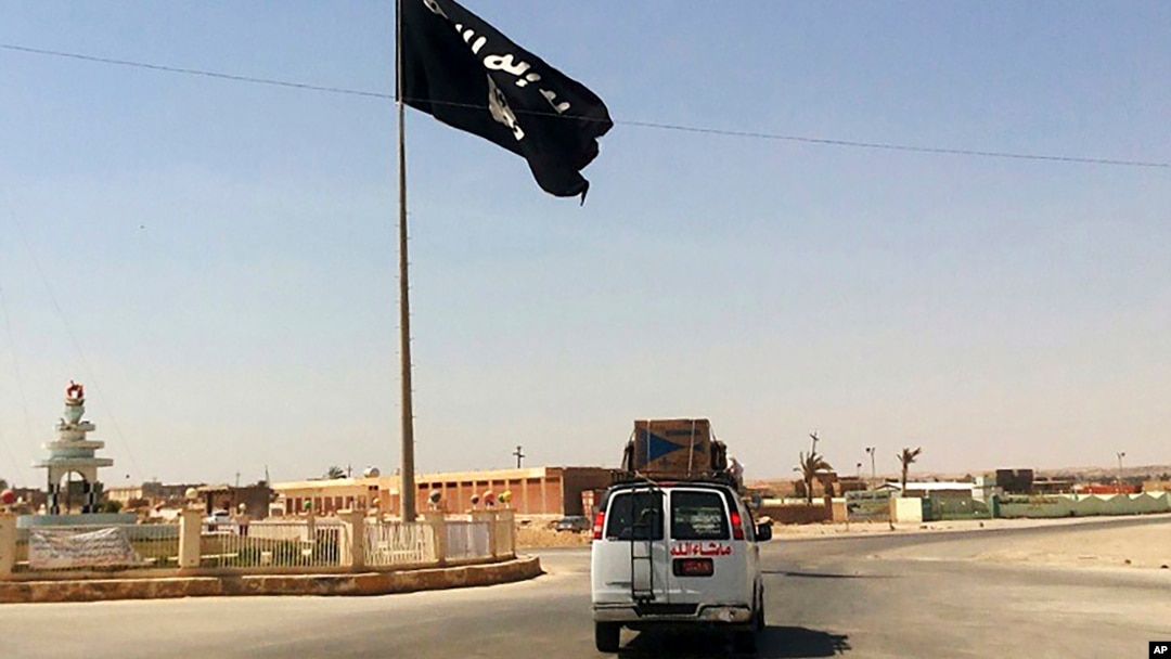 En esta imagen de archivo tomada el 22 de julio de 2022 muestra un vehículo al momento de pasar junto a una bandera del grupo Estado Islámico en el centro de Rawah, una ciudad a 281 kms (175 millas) al noroeste de Bagdad.