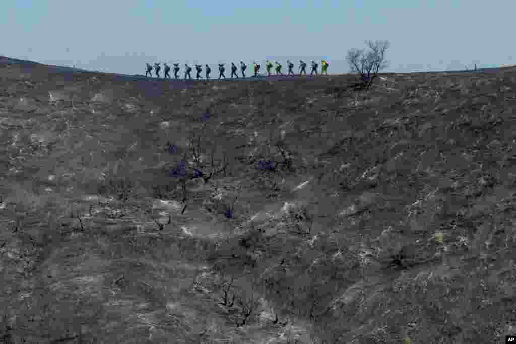 Fire crews walk along a blackened ridge as they battle the Getty fire, Oct. 28, 2019, in Los Angles.