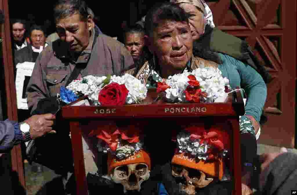 A woman carries decorated human skulls after praying in the chapel at the General Cemetery during the "Natitas" festival in La Paz, Bolivia.