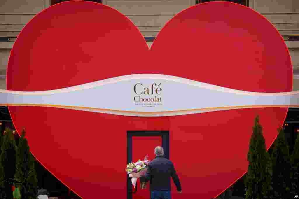 A man holds flowers as he walks to a cafe decorated for Valentine's Day, in Bucharest, Romania.