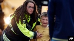 Officials guide students off a bus and into a recreation center where they were reunited with their parents after a shooting at a suburban Denver middle school in Highlands Ranch, Colorado, May 7, 2019. 